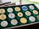 Collection of luxury golf ball markers in sterling silver and gold displayed on a green velvet surface