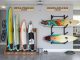 A vertical wooden surfboard stand holding two boards in a bright living room.