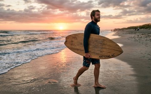Person carrying a skimboard safely on a North Carolina beach.