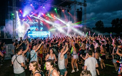 Crowd dancing under stage lights at an outdoor electronic music festival