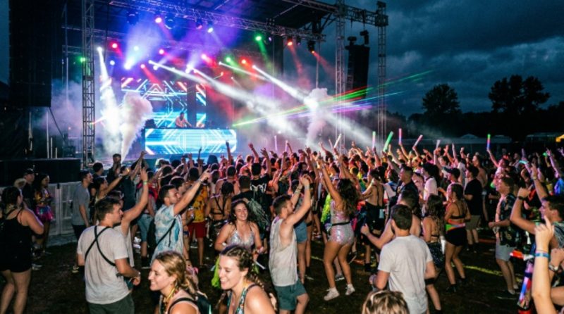 Crowd dancing under stage lights at an outdoor electronic music festival